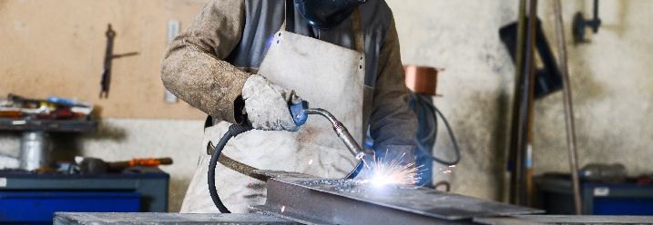 Mann schweißt in einer Werkstatt heißen Stahl mit GMAW Schweißer und Schutzausrüstung
